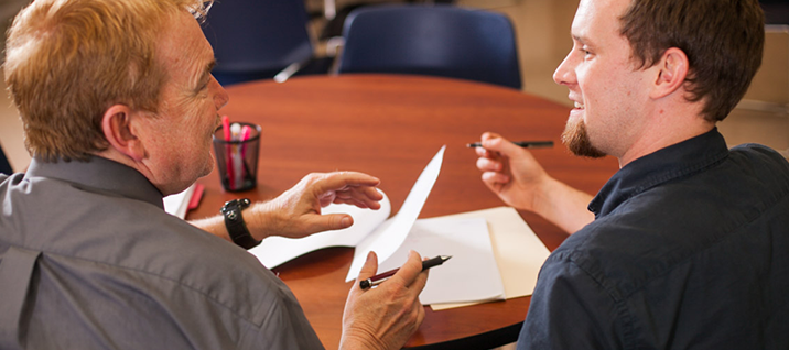 Two male students discussing the papers on the table