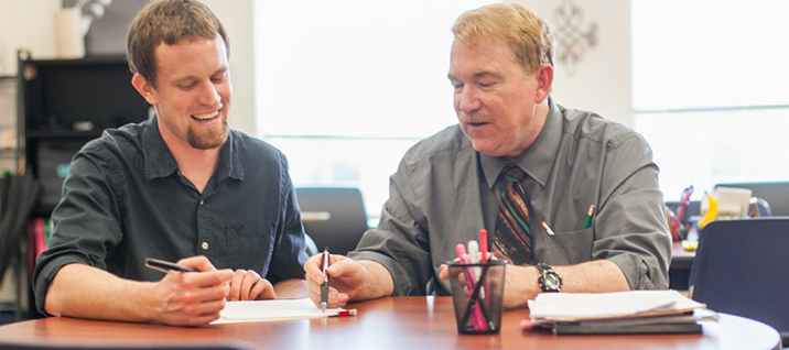 A teacher discusses English Composition with a smiling student