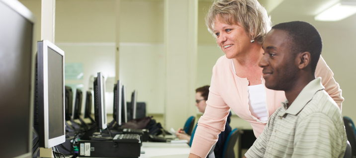 Teacher helping student in computer lab