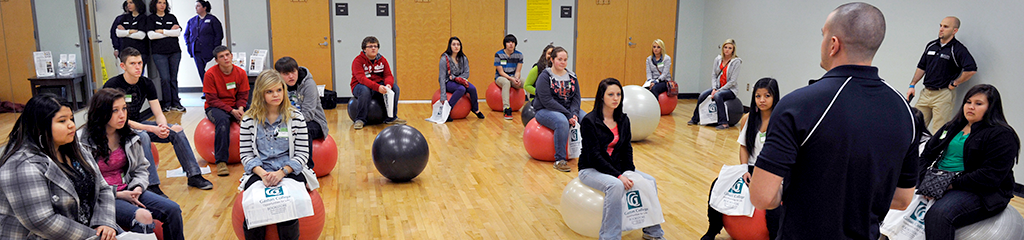 Fitness class in aerobics room sitting on exercise balls