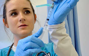 Female nursing student filling a syringe with medicine