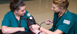 Nursing student tests fellow student's blood pressure