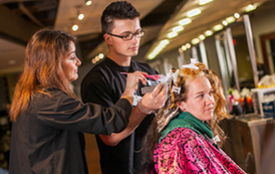 Image of cosmetology students working on a clients hair-do