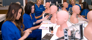 Female students apply makeup to manikins