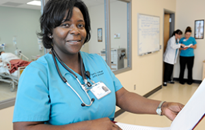 Female nursing student smiling at camera in hallway of hospital