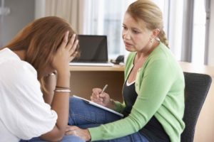 Young Woman Having Counseling Session With Head In Hands.