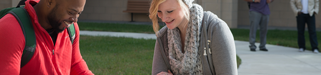Tow students sit together reading on Dallas Campus