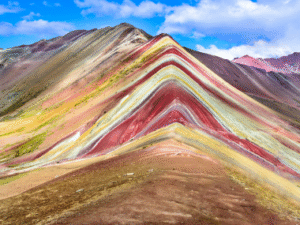 Rainbow Mountain on the Inca Trail in Peru. Multi-colored mountain mineral peaks with blue sky and white puffy clouds in the background in Peru,
