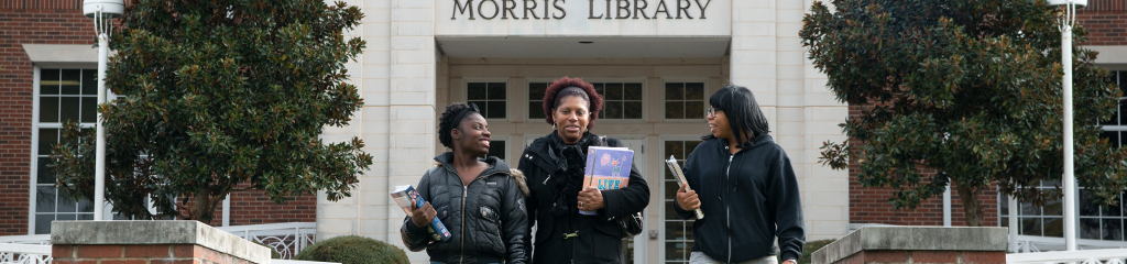 Three female students talk together as they walk the Dallas Campus