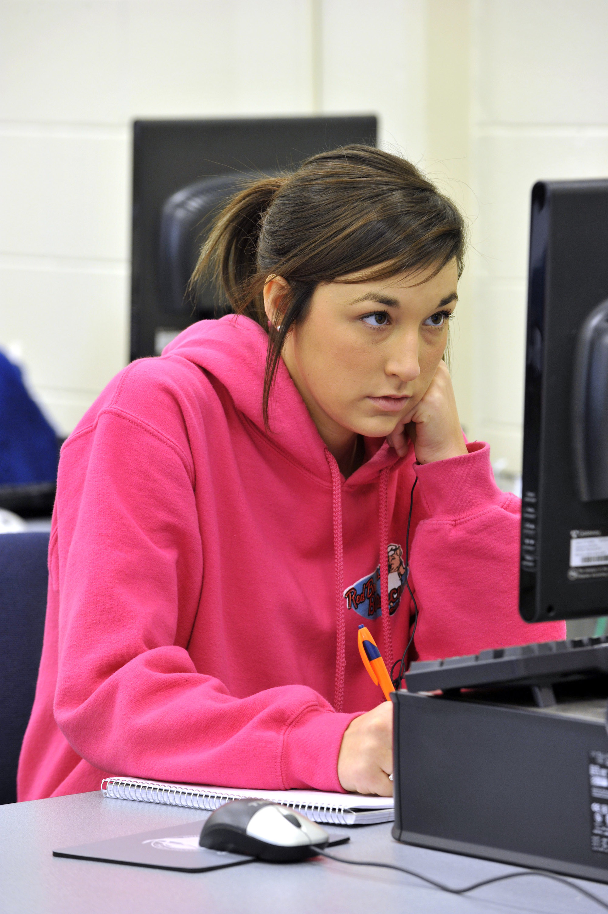 Female students looks at computer while writing in notebook in computer lab
