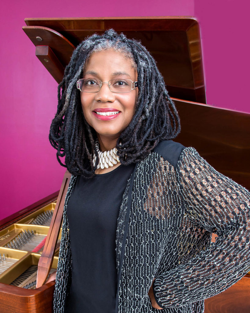 Woman smiling and posing in front of musical instruments