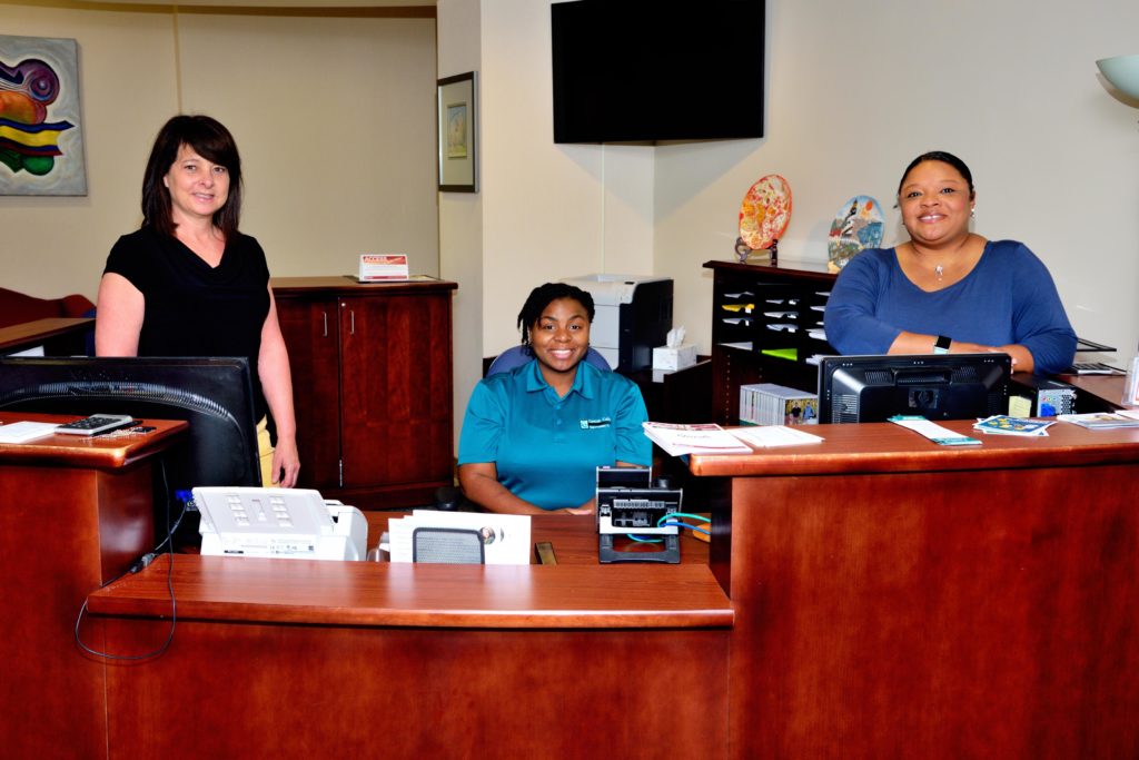 Three female counselors posing behind desk