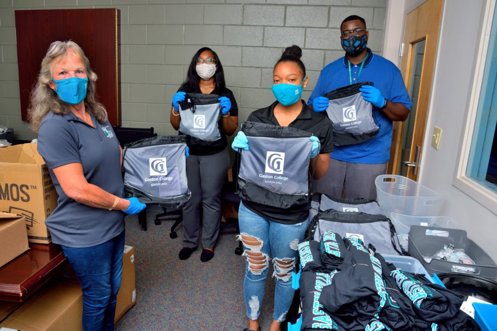 four people wearing masks and holding backpacks