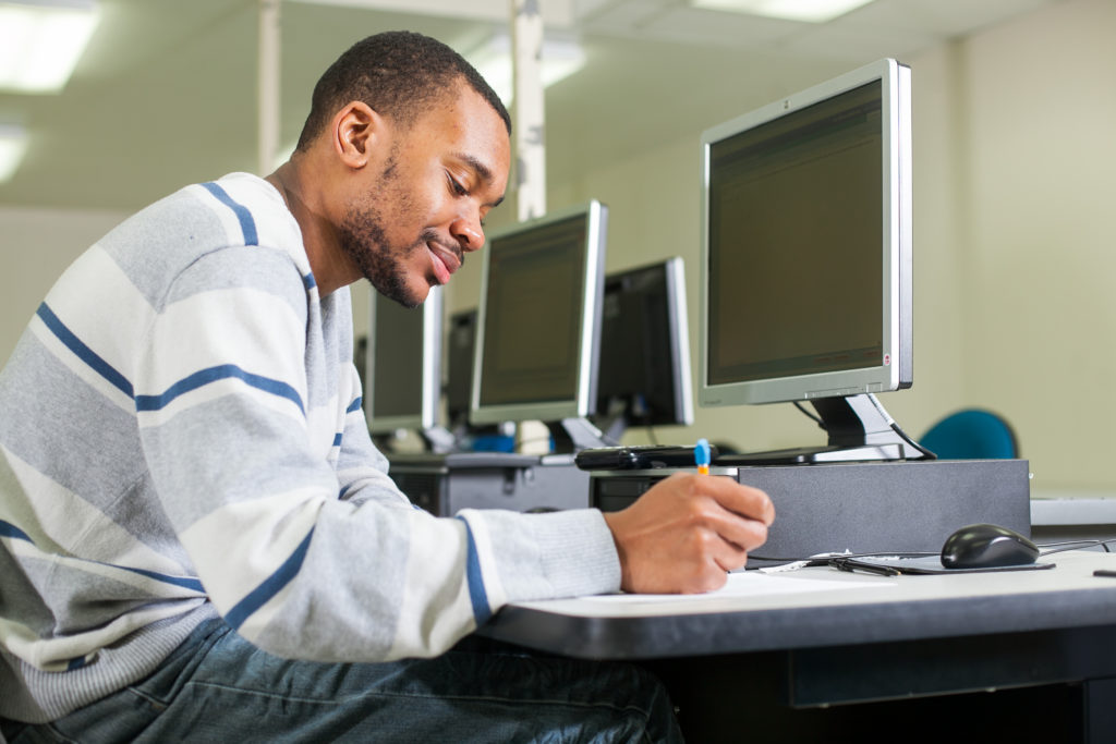 male student doing work in a computer lab