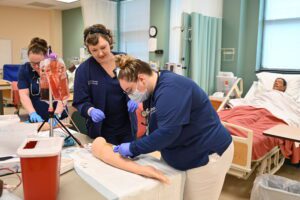 Nursing faculty helps student in classroom