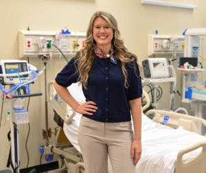 Outstanding Respiratory Therapy Graduate, Jenna Parker smiling with long hair standing in medical hospital room.